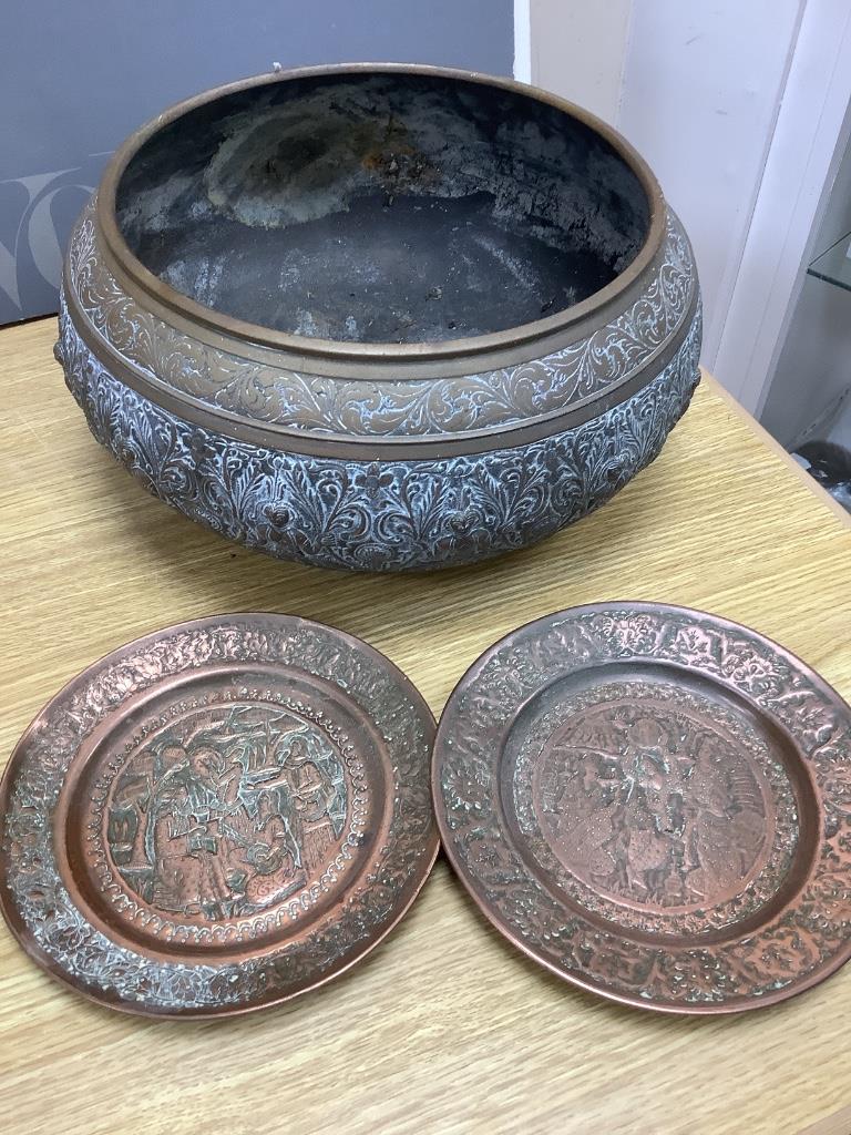 A large Eastern brass bowl cast with bands of seated deities, foliate scrolls and linear decoration and a pair of copper dishes